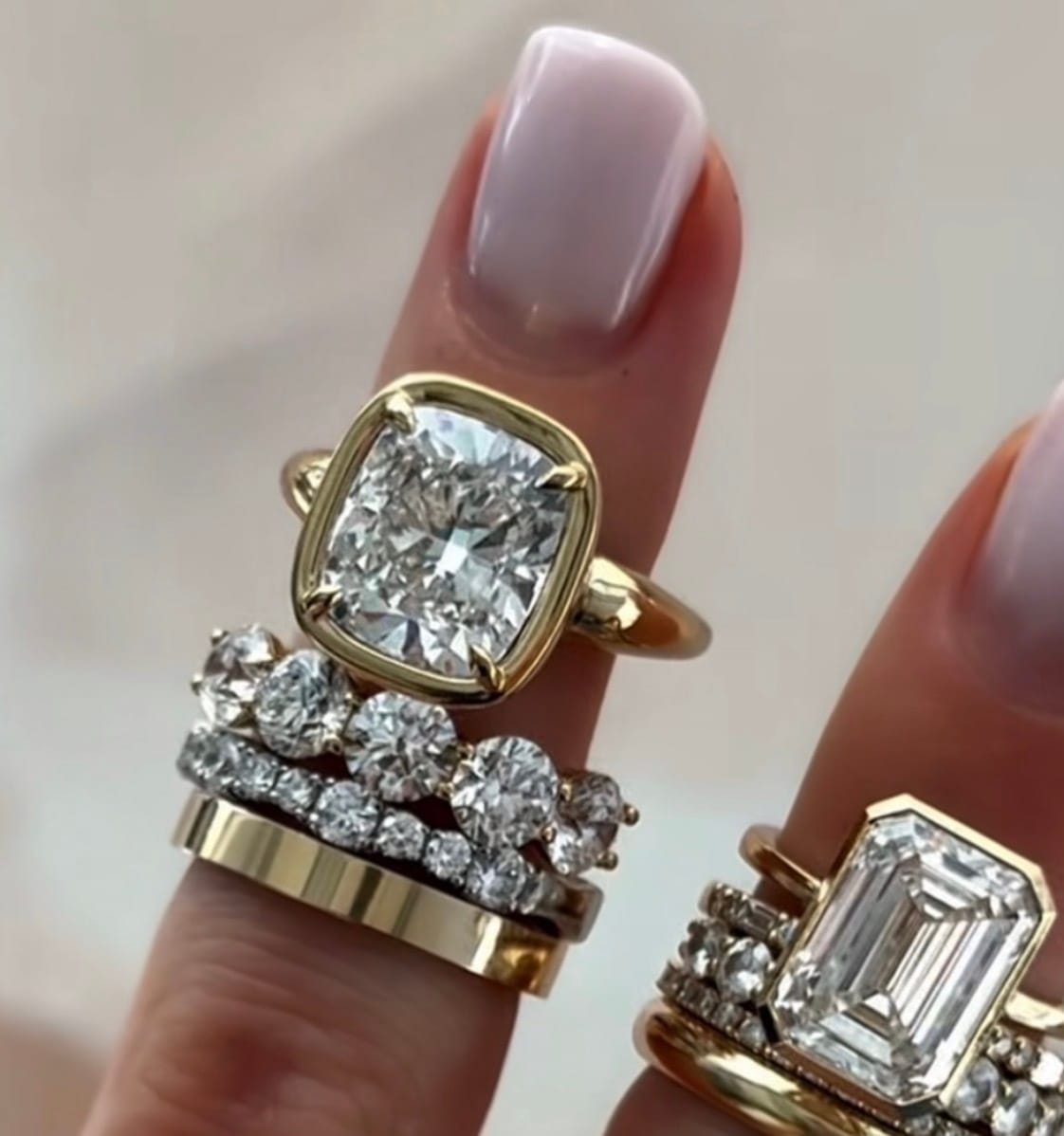 Cushion and emerald-cut diamond rings stacked in yellow gold