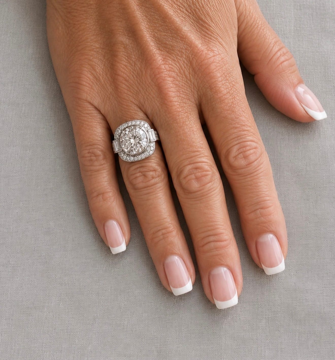 Round brilliant diamond in a cushion halo with baguette shoulders