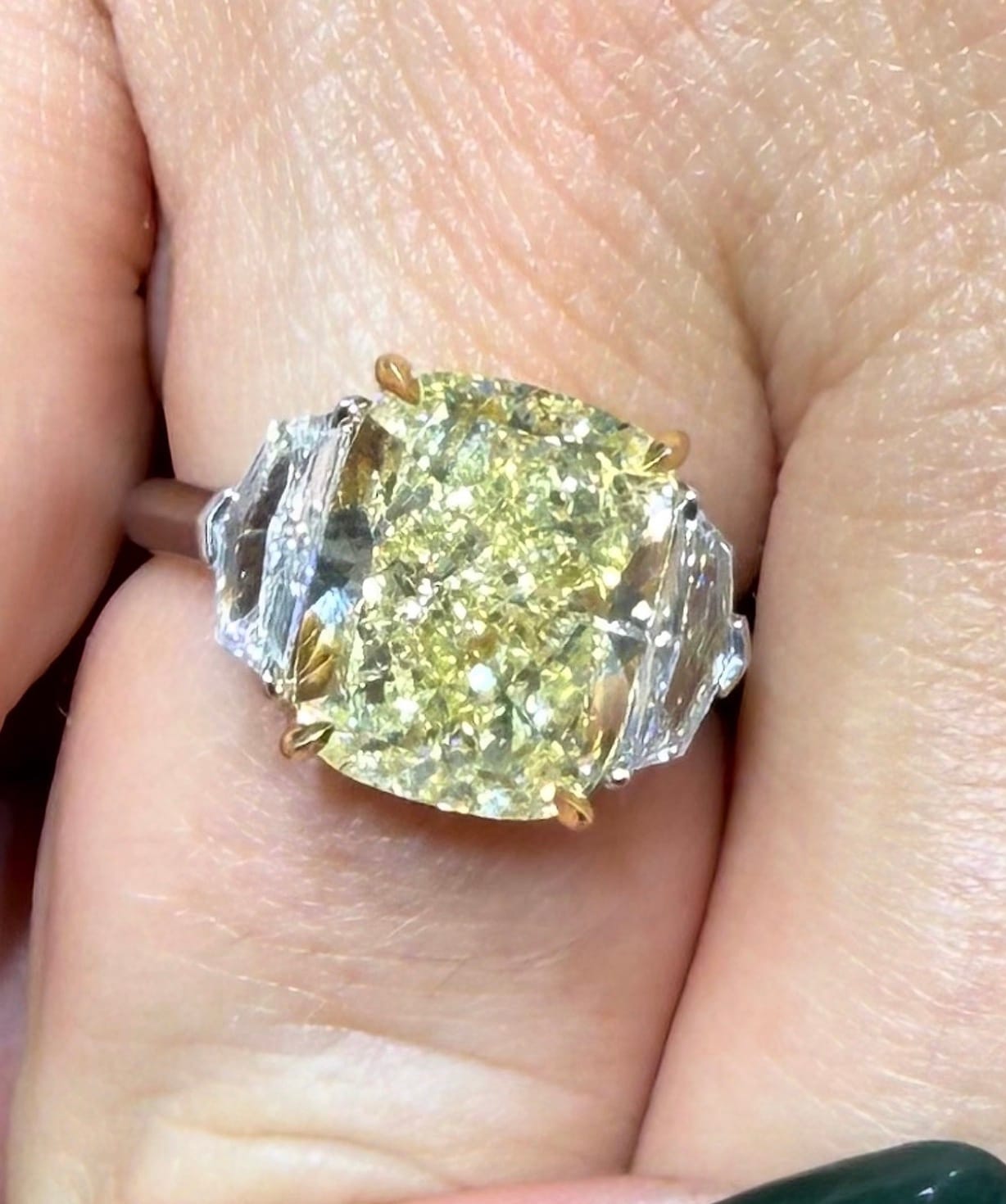 A fancy yellow cushion diamond, three-stone ring